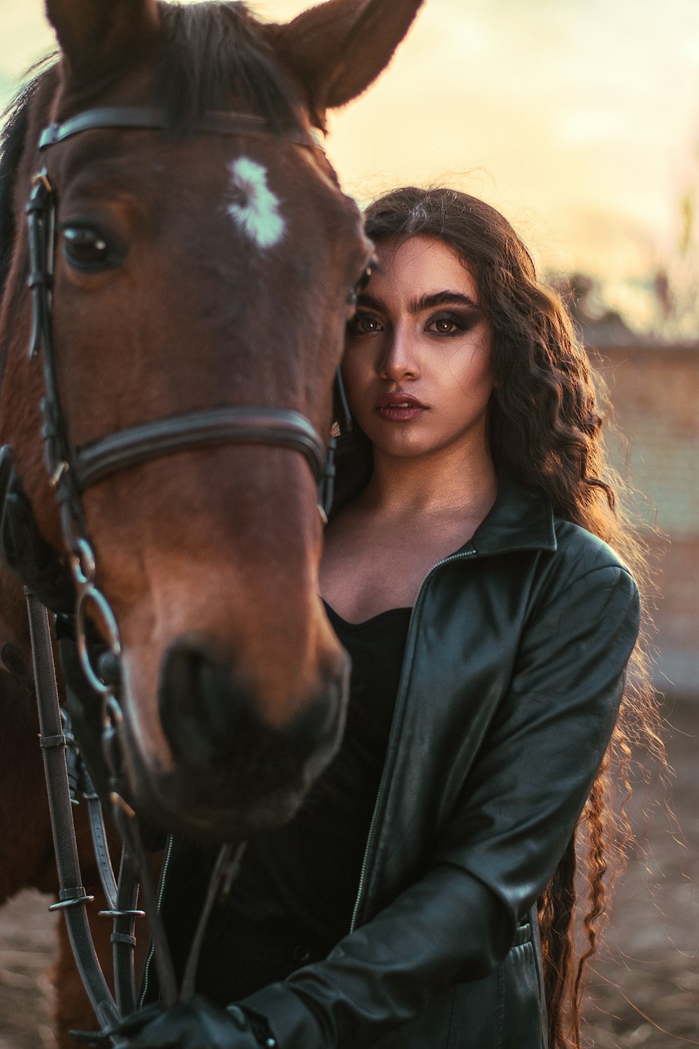 woman in black leather jacket beside brown horse during daytime