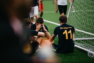 group of men in black and yellow crew neck t-shirts sitting on green grass field