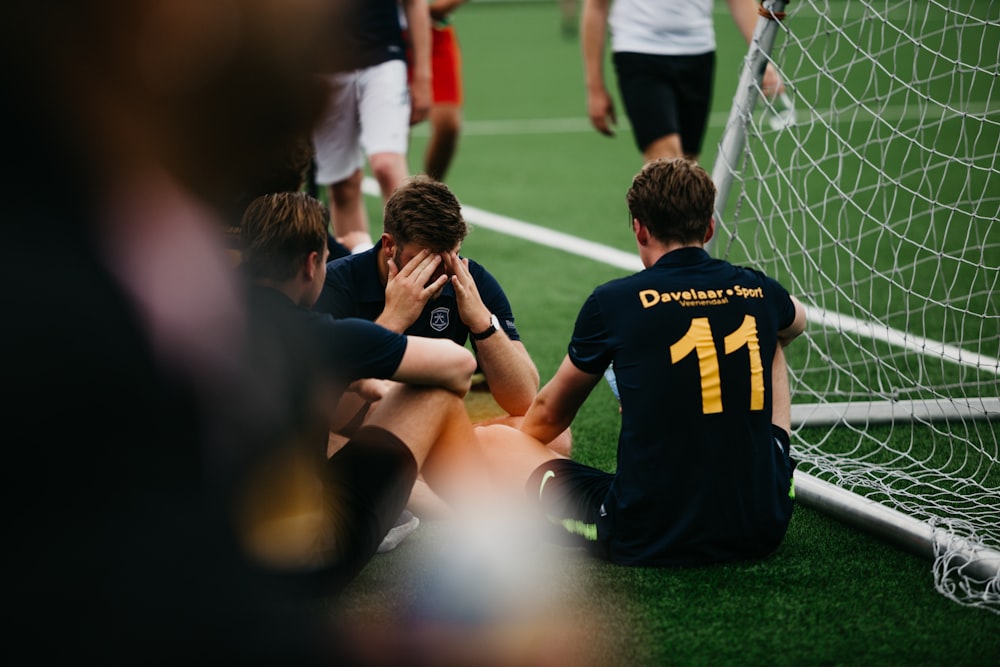 group of men in black and yellow crew neck t-shirts sitting on green grass field