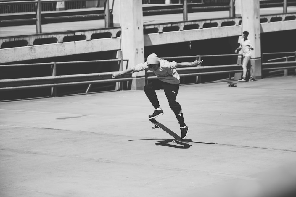 man in white long sleeve shirt and black pants playing skateboard