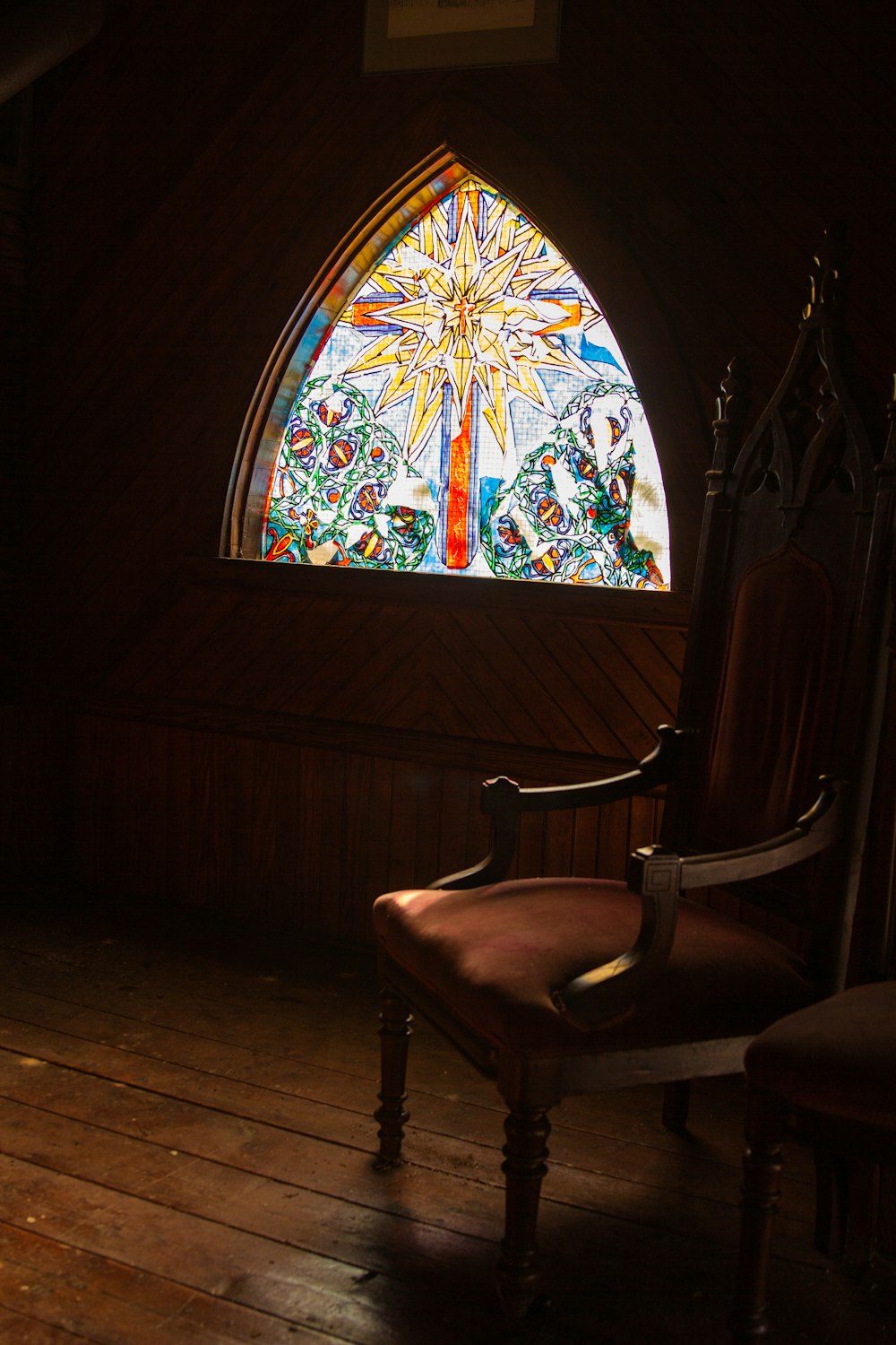 brown wooden armchair beside window