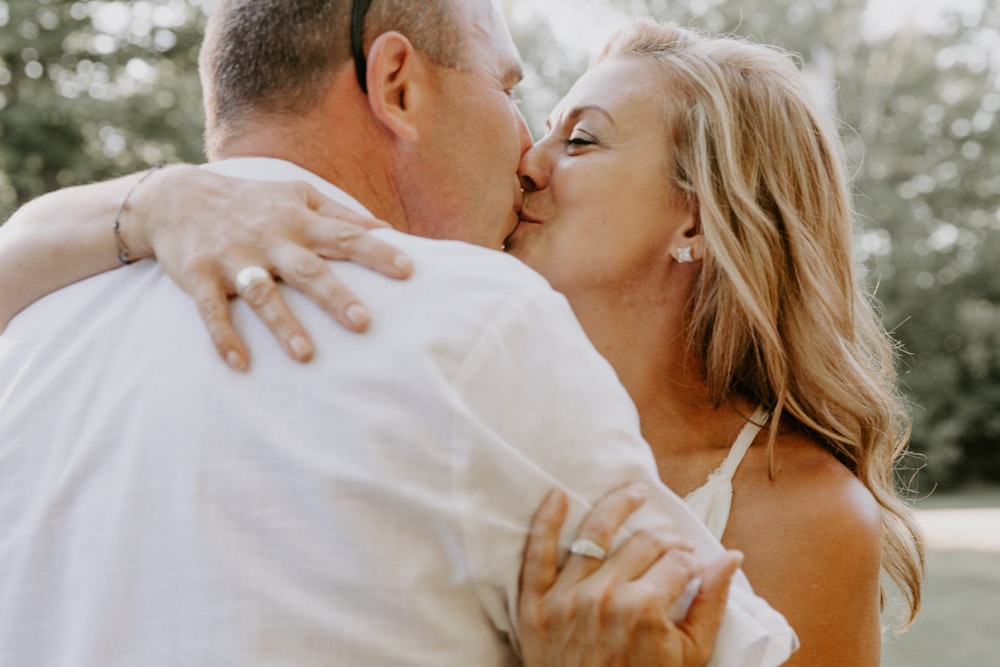 man in white shirt kissing woman in white spaghetti strap top