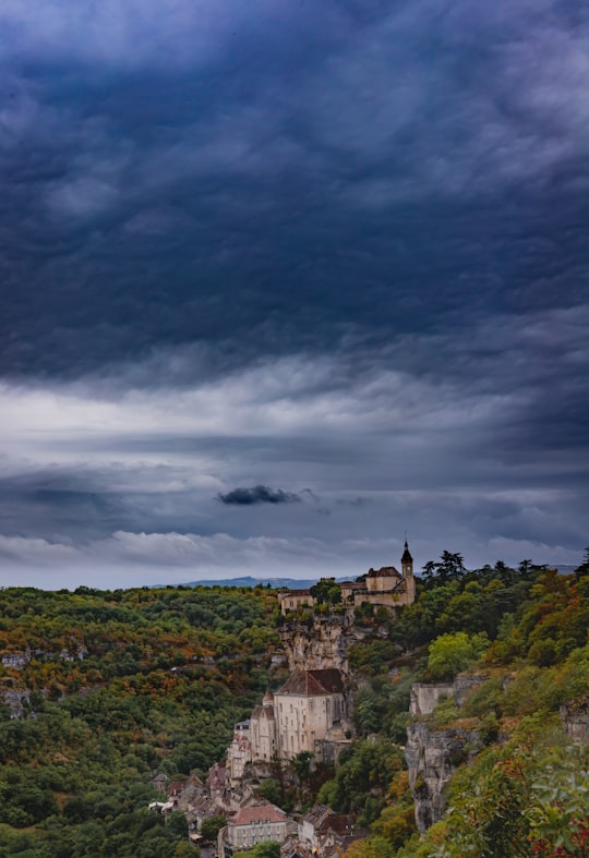 gray concrete building on top of hill under gray clouds in Causses du Quercy Natural Regional Park France
