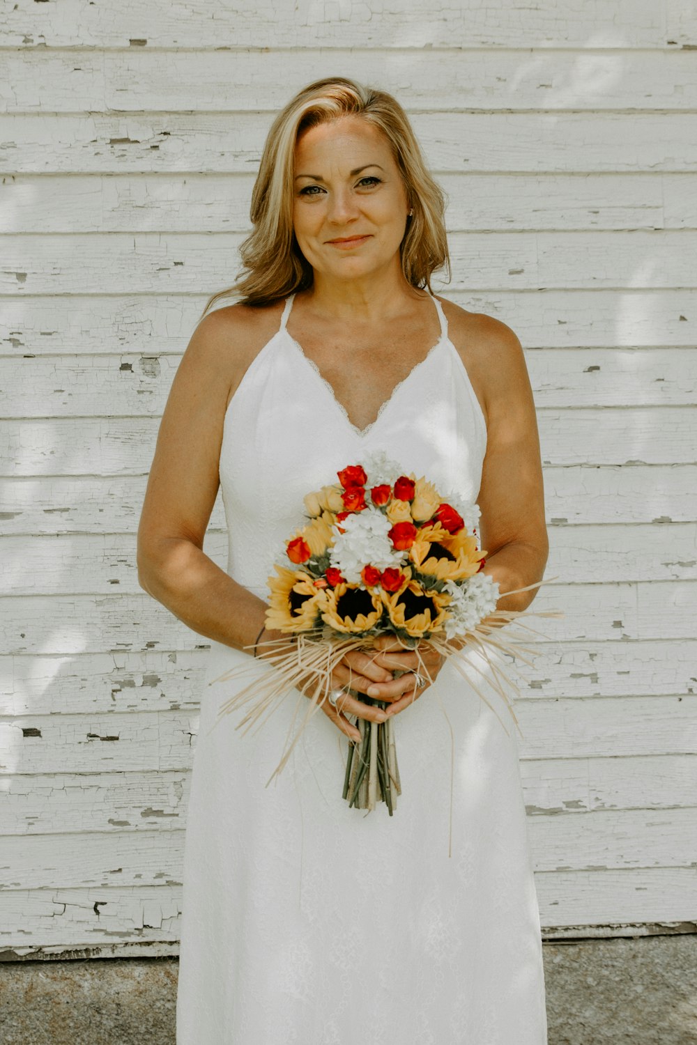 Frau in weißem ärmellosem Kleid mit Blumenstrauß