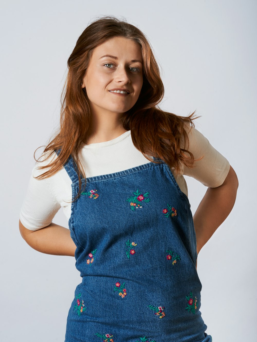 Fille en chemise blanche à manches longues et salopette en jean bleu