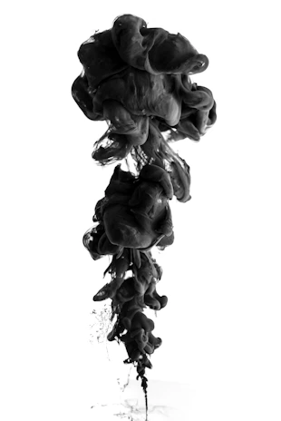 A swirling pool of black ink dissolving into deep charcoal shadows.