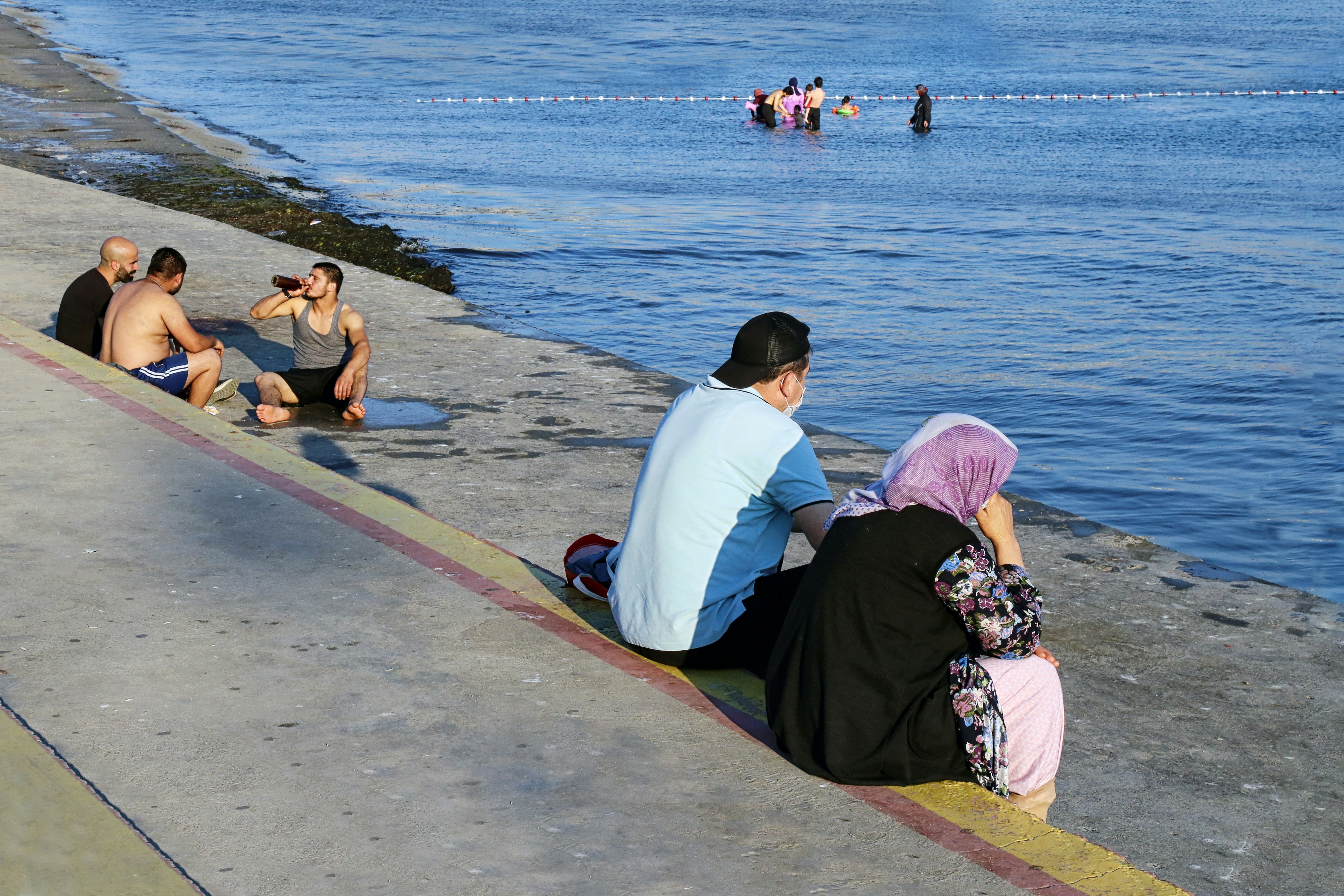 man and woman sitting on concrete dock near body of water during daytime