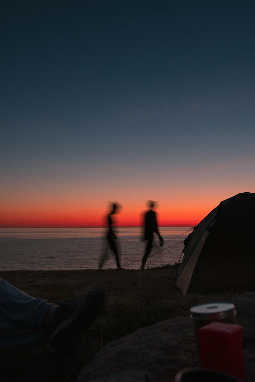 silhouette of 2 person standing beside tent during sunset