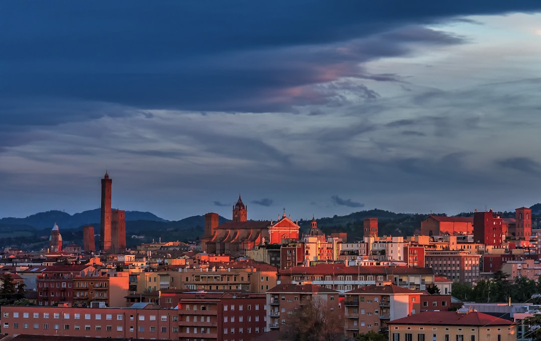 brown and white concrete buildings under blue sky, Bologna skyline and towers in evening sunset