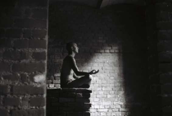 A serene professional in a navy suit meditating calmly in a modern office space with golden accents.