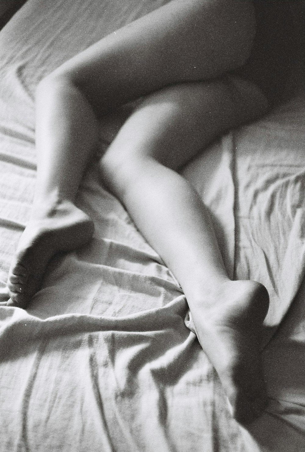 grayscale photo of woman lying on bed