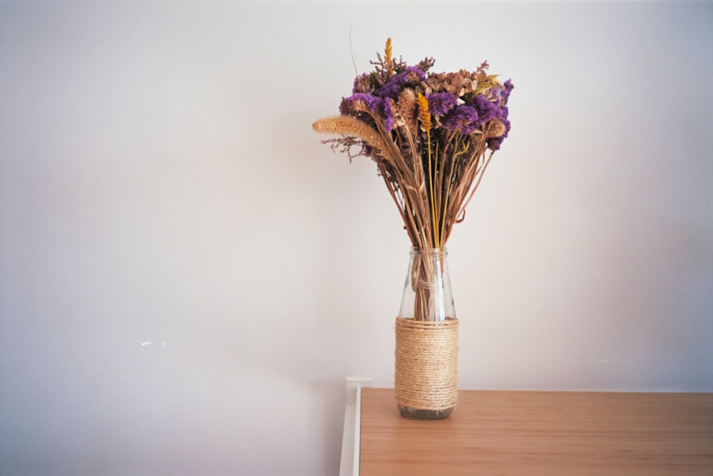 purple and yellow flowers in clear glass vase