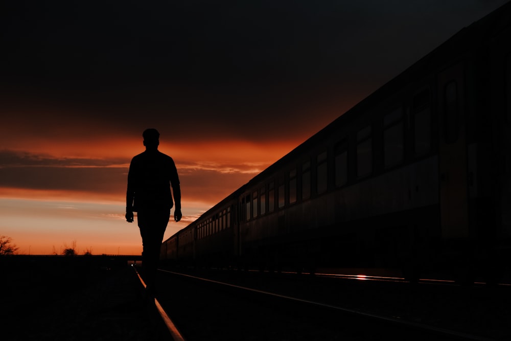 silhouette dell'uomo che cammina sul ponte durante il tramonto