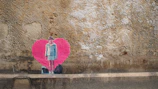 A vibrant Banksy mural of a girl releasing a heart-shaped balloon on a weathered brick wall.