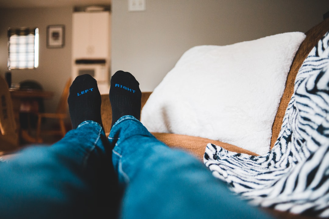 person in blue pants and black socks lying on bed
