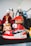 A collection of colorful figurines stands prominently, with the focus on a sneaker-styled toy figure. The shoe features a vivid red and white color scheme with black accents and recognizable branding. Surrounding it are various other figures, each with unique costumes and vibrant details.