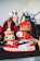 A collection of colorful figurines stands prominently, with the focus on a sneaker-styled toy figure. The shoe features a vivid red and white color scheme with black accents and recognizable branding. Surrounding it are various other figures, each with unique costumes and vibrant details.