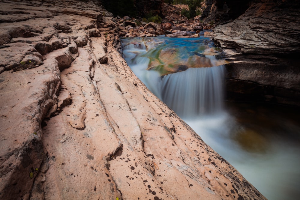 body of water between brown rocks during daytime