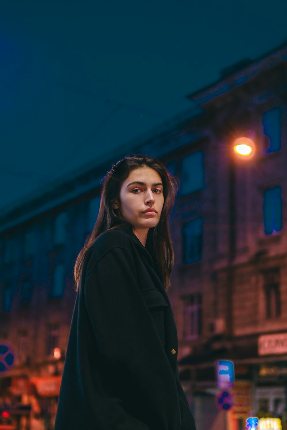 a woman standing on a street corner at night