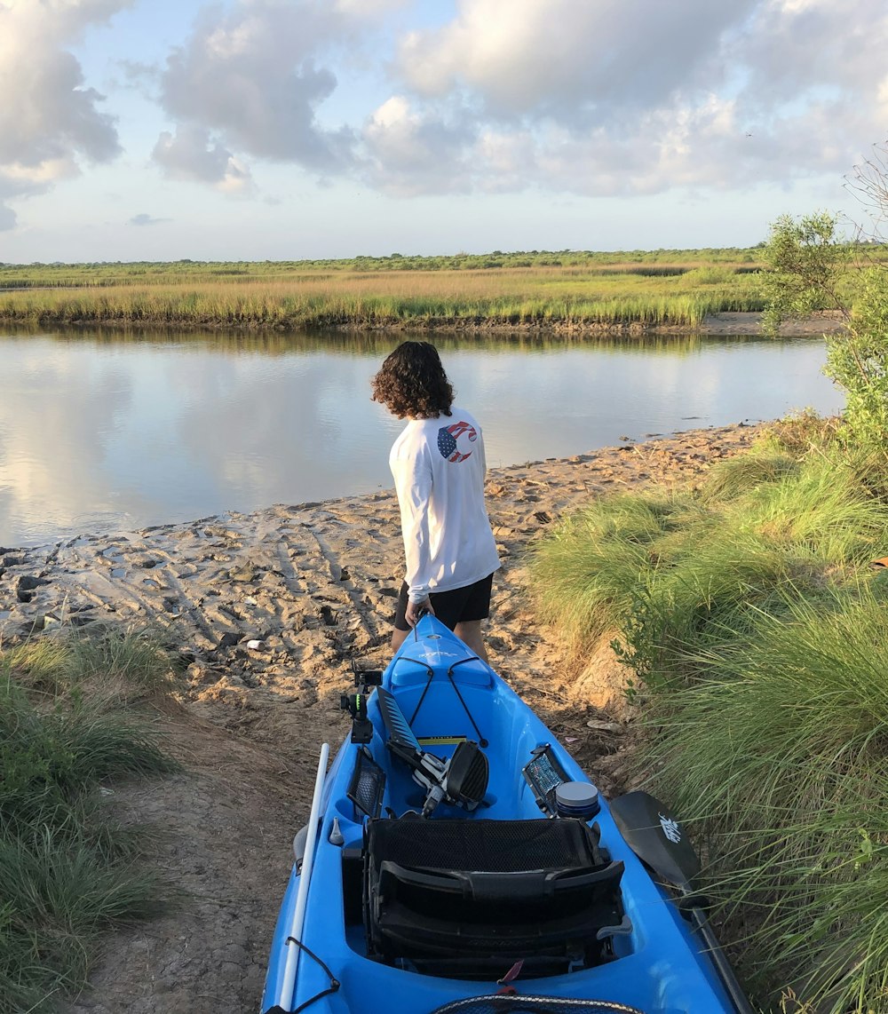 Mujer con camisa blanca sentada en un bote azul en el río durante el día