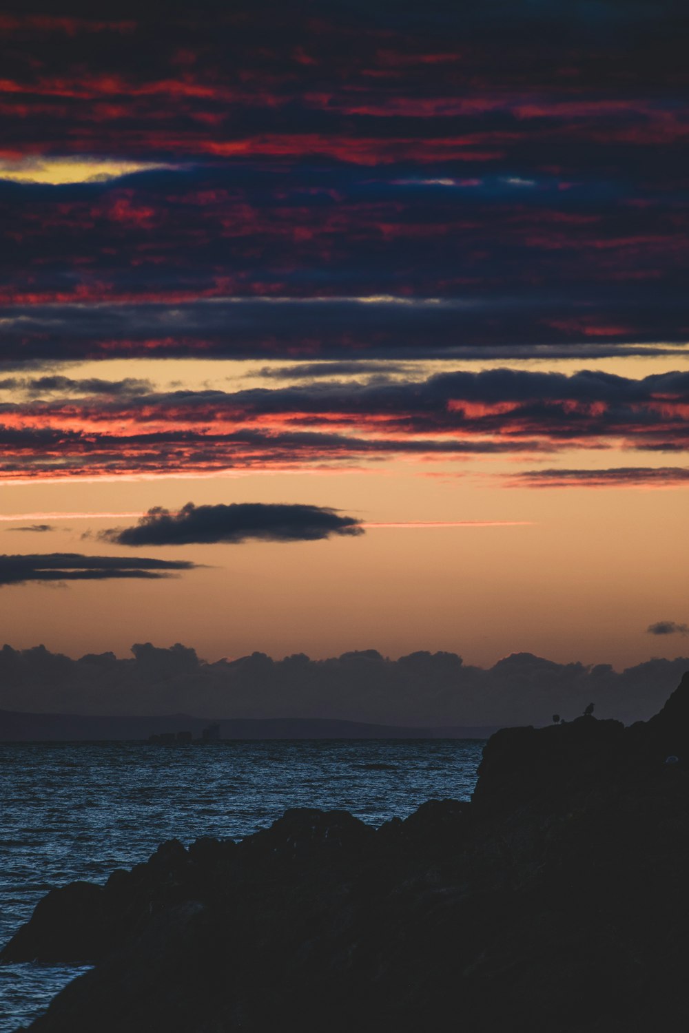 silhouette of mountain near body of water during sunset