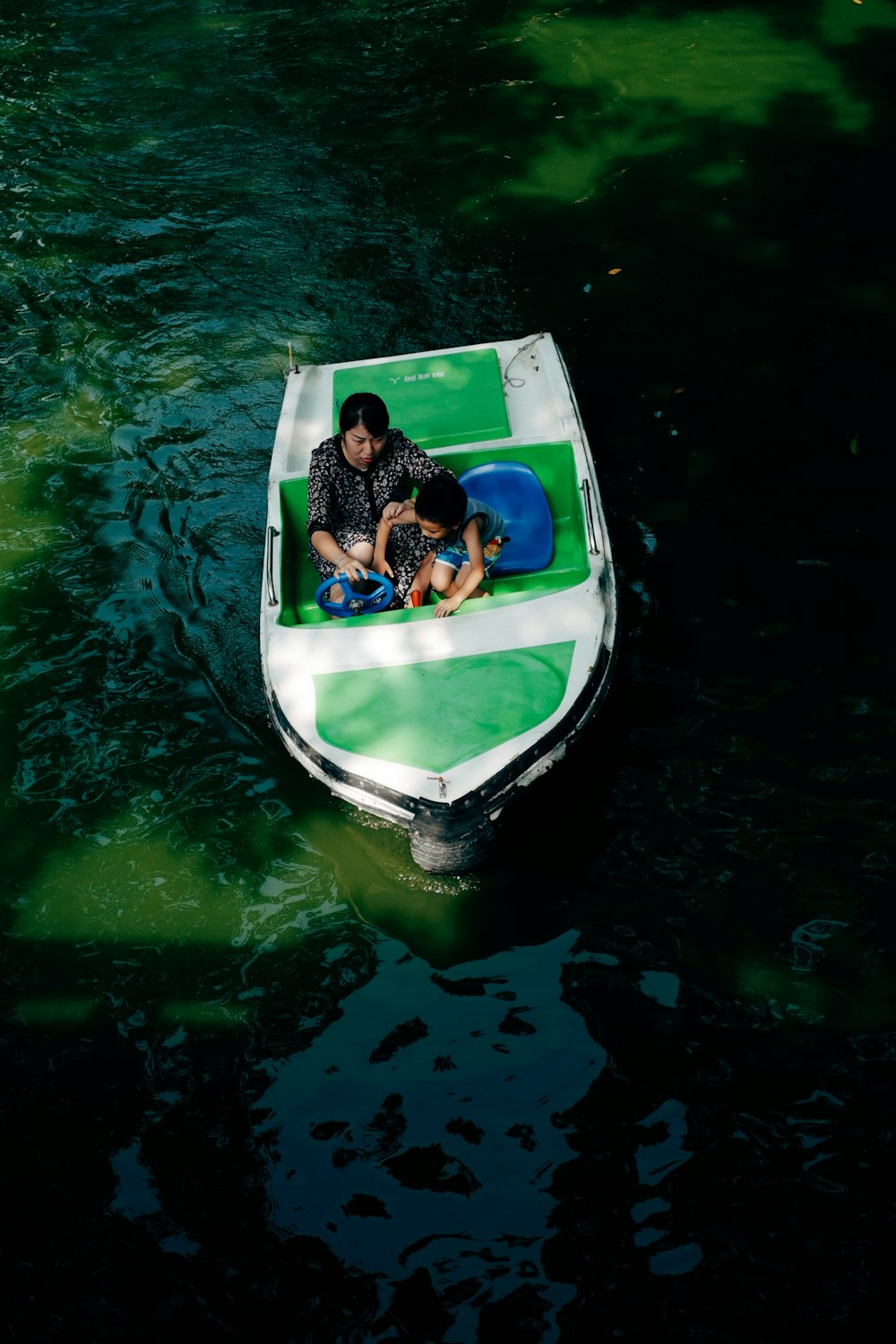 Mujer en vestido blanco y negro sentada en barco blanco y azul en el agua durante el día