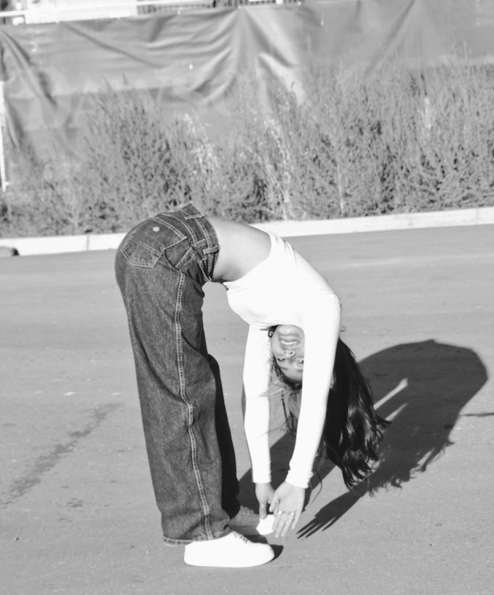 woman in white tank top and blue denim jeans standing on road