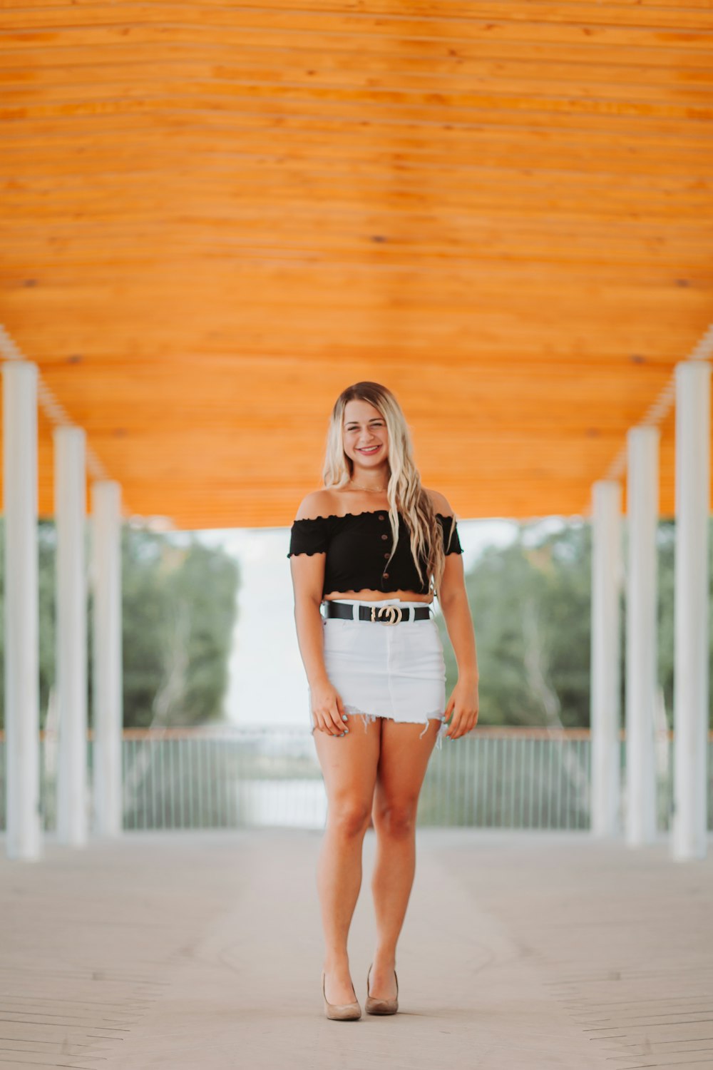 Femme en t-shirt noir et short en jean bleu debout sur un plancher en bois brun