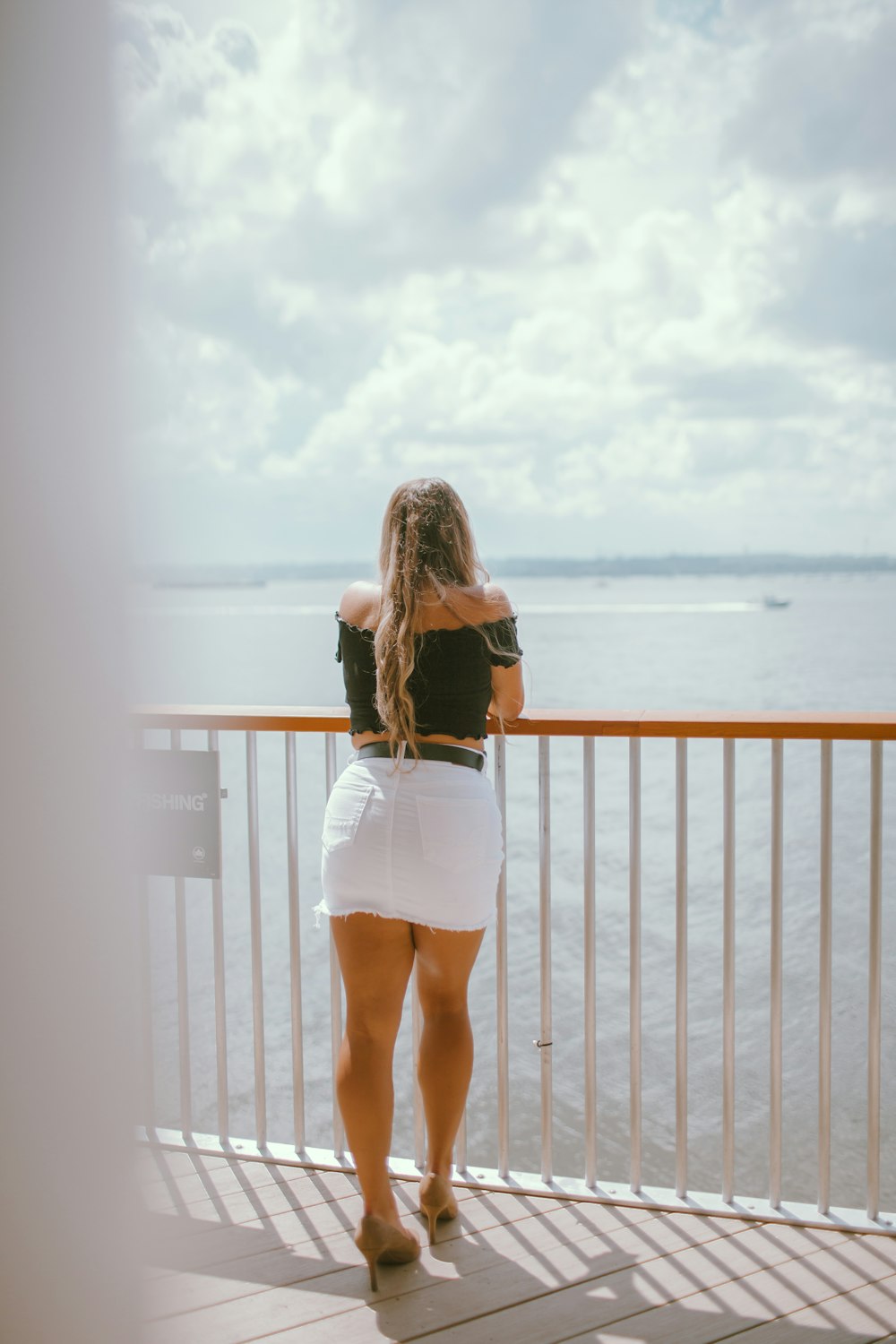 woman in white mini dress standing on brown wooden dock during daytime