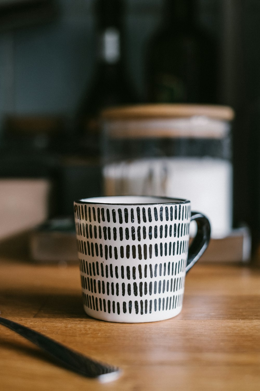 white and black ceramic mug on brown wooden table
