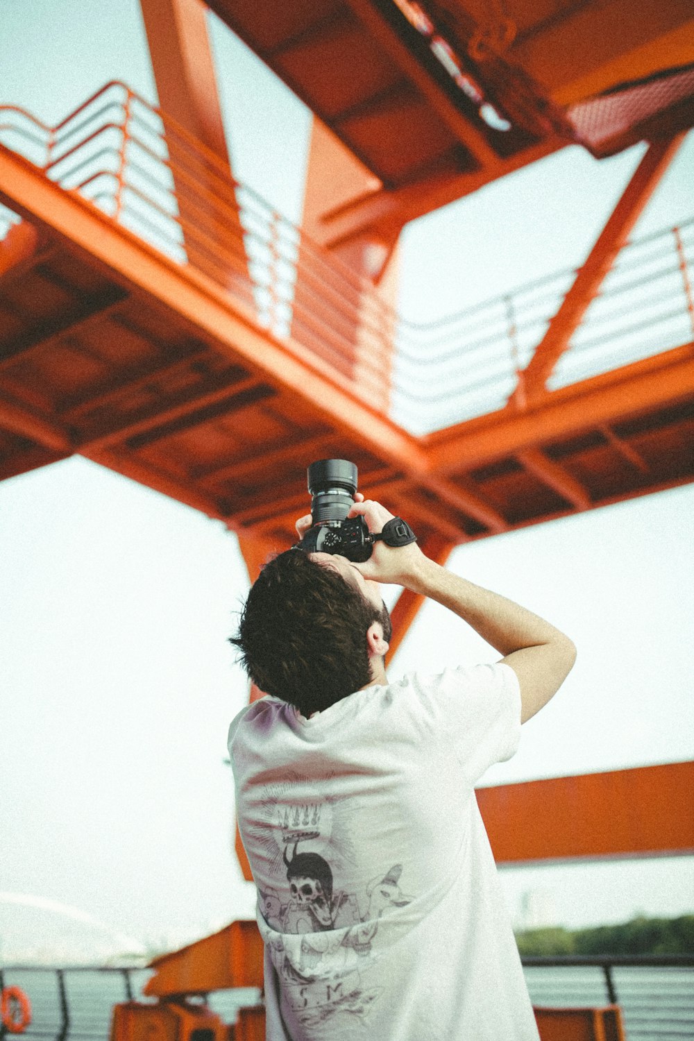 man in white t-shirt holding black dslr camera