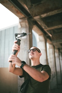 man in black crew neck t-shirt holding gray metal tool