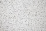 A close-up view of a textured white popcorn ceiling, characterized by its bumpy and uneven surface.