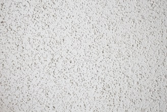 A close-up view of a textured white popcorn ceiling, characterized by its bumpy and uneven surface.