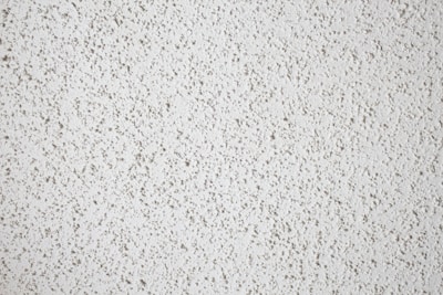 A close-up view of a textured white popcorn ceiling, characterized by its bumpy and uneven surface.
