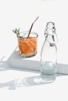 clear glass bottle beside orange juice in clear glass bottle