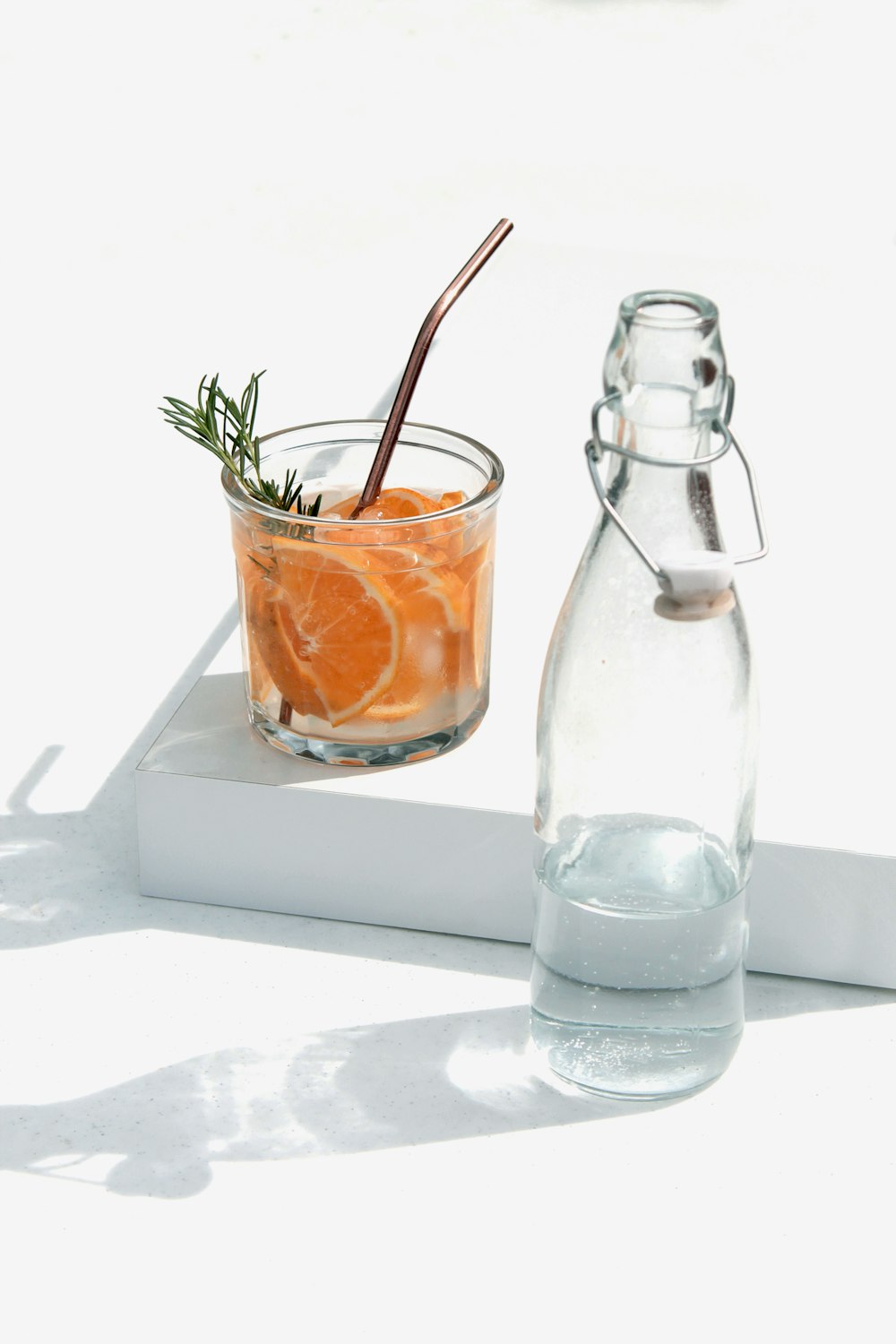clear glass bottle beside orange juice in clear glass bottle