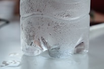 Close-up of clear bottled water with condensation droplets on the label.
