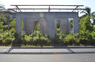 A clean, level concrete slab ready for a new home build, set against a backdrop of lush Oahu greenery.