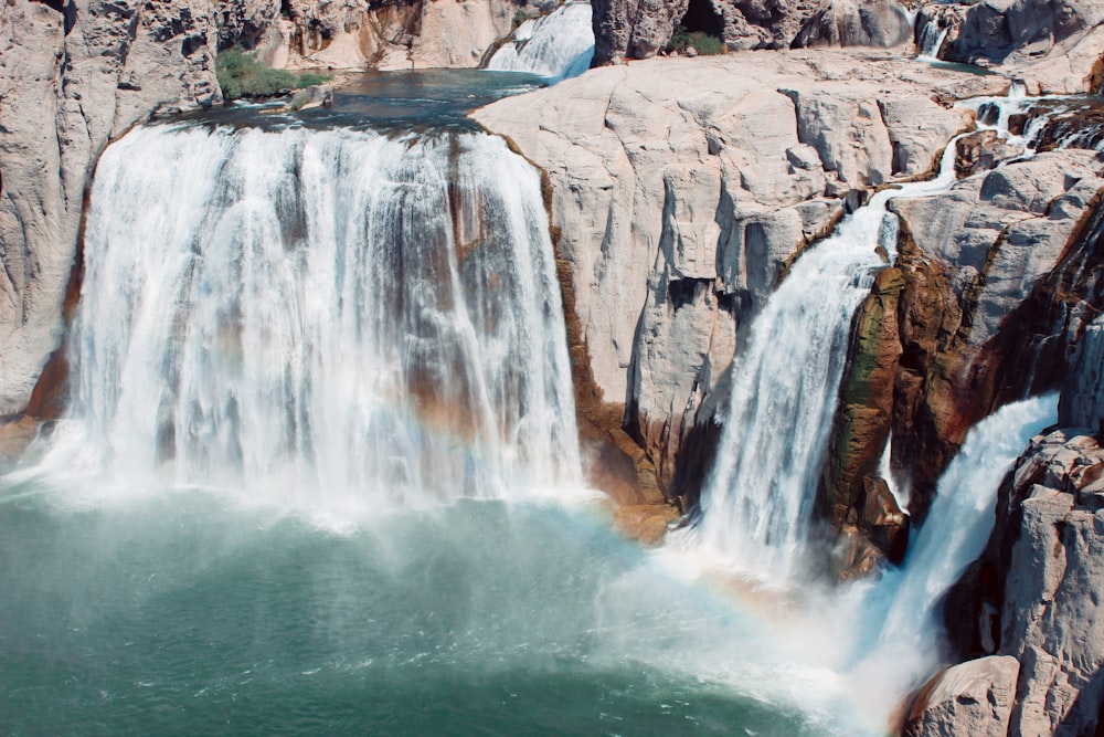 water falls on brown rocky mountain during daytime