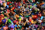 A chaotic assortment of colorful toys piled together, including action figures, plush animals, vehicles, and various shapes and characters. The variety of toys suggests a playful and imaginative setting.