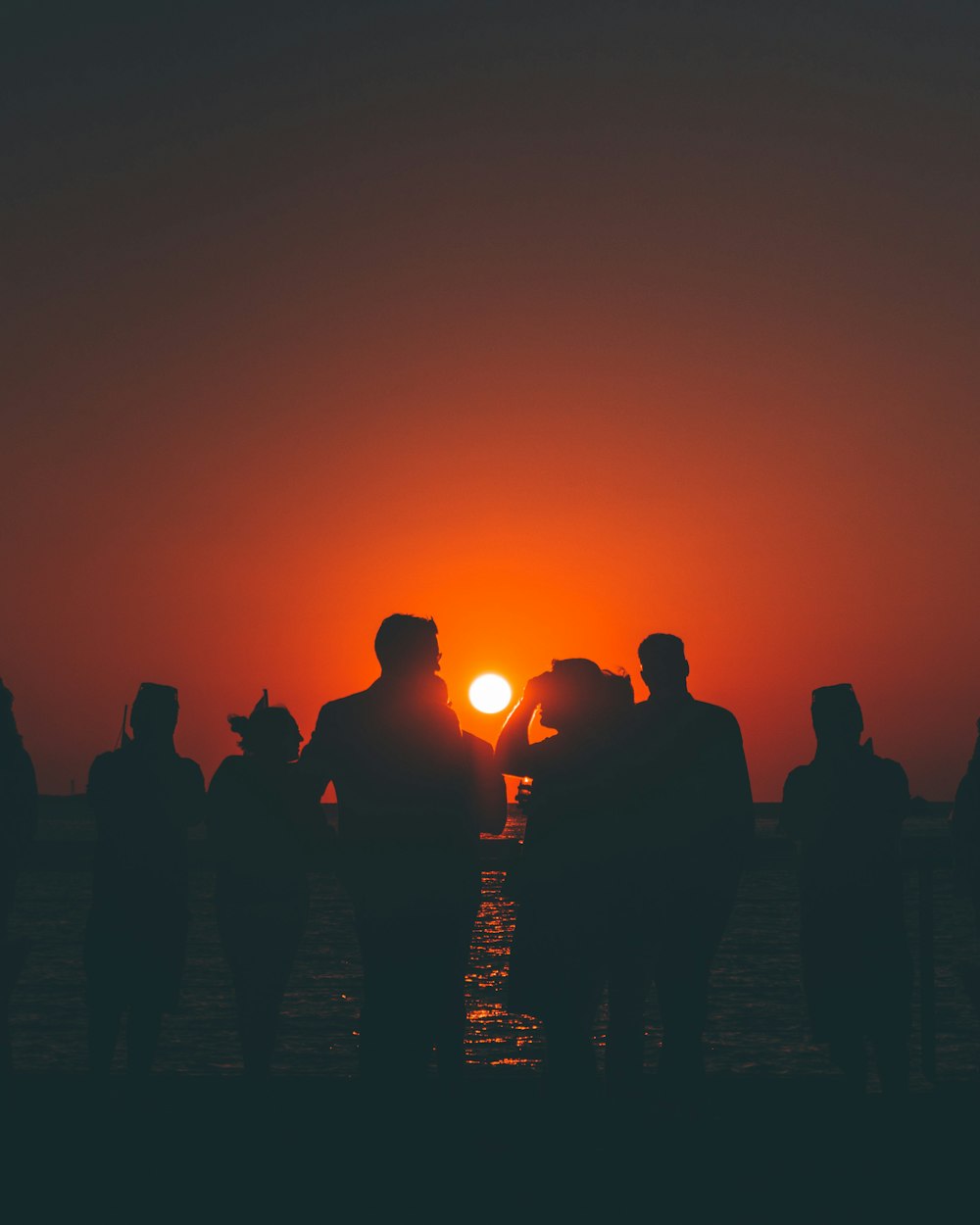 silhouette of people standing on beach during sunset