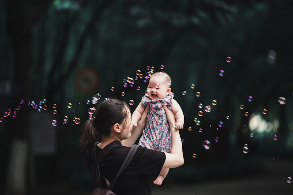 girl in black and pink dress blowing bubbles