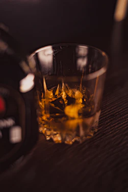 A close-up of a crystal whisky glass catching the warm glow of a cozy lounge.