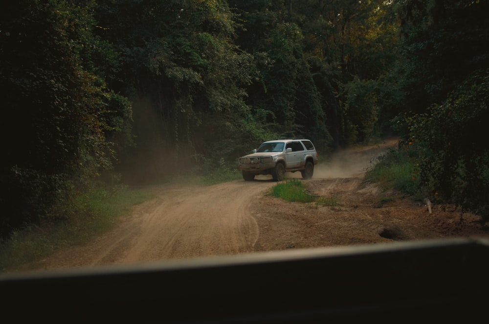 white suv on dirt road during daytime