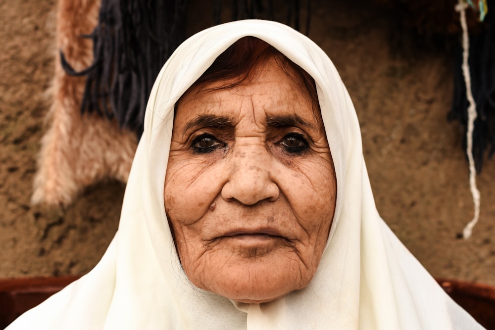 woman in white hijab standing near brown rock