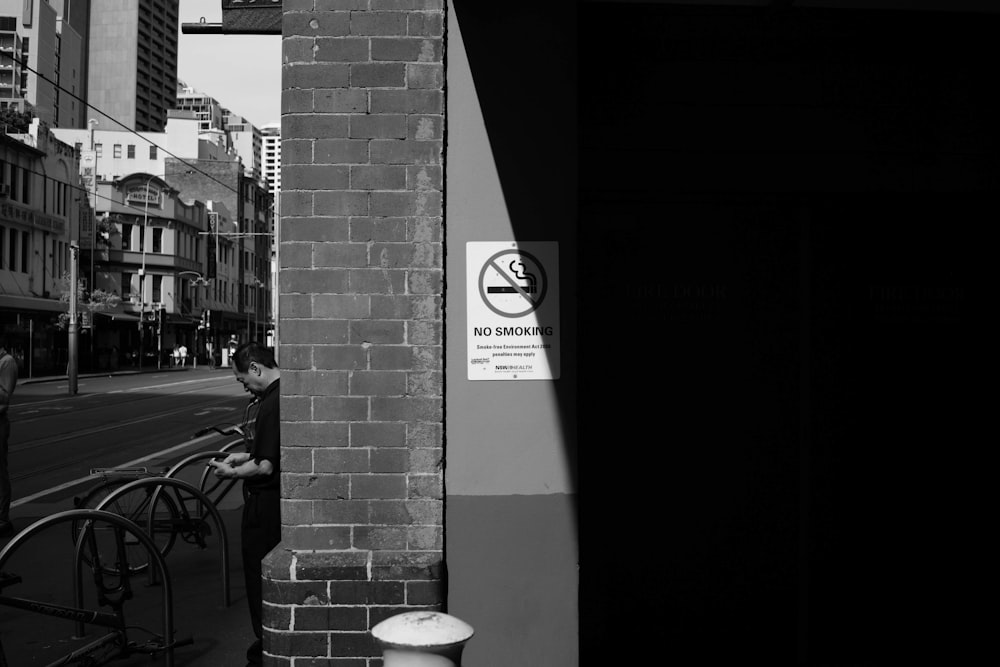 grayscale photo of a man standing near the wall