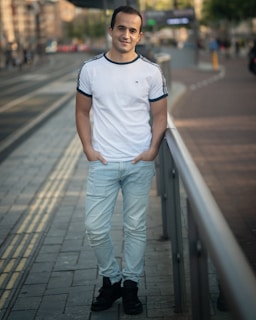 A casual outfit featuring a crisp white t-shirt paired with dark jeans and sneakers on a city street.