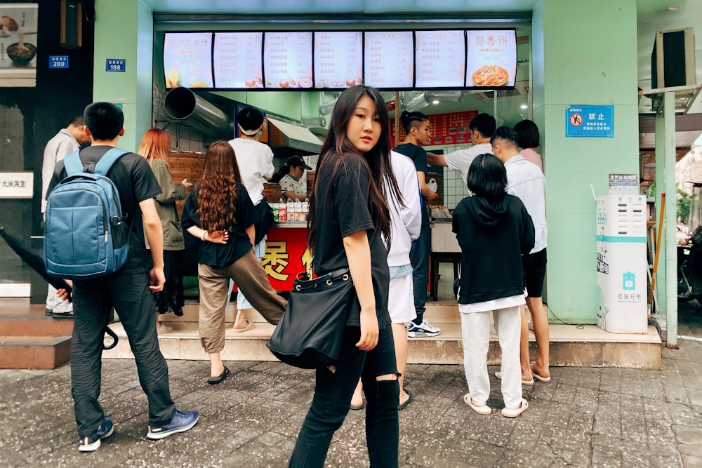 woman in black shirt and blue denim jeans standing in front of store