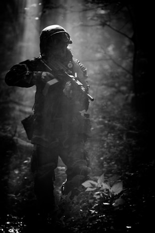 A rugged soldier silhouette against a smoky battlefield at dawn.